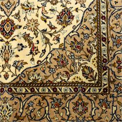 Central Persian Kashan hand-knotted rug, ivory ground, with a central shaped floral medallion with pendants, surrounded by scrolling foliate and floral motifs incorporating rosettes, palmettes and delicate vine work, enclosed by a beige border with repeating palmettes and meandering vines, flanked by narrow floral guard stripes, with cotton fringes