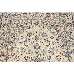 Central Persian Nain hand-knotted silk and wool rug, ivory field with a cusped medallion  issuing radiating pendants, with an all-over design of scrolling arabesques, palmettes and floral sprays, framed main border of meandering vinery and stylized palmettes, flanked by narrow guard stripes, cotton fringe ends  