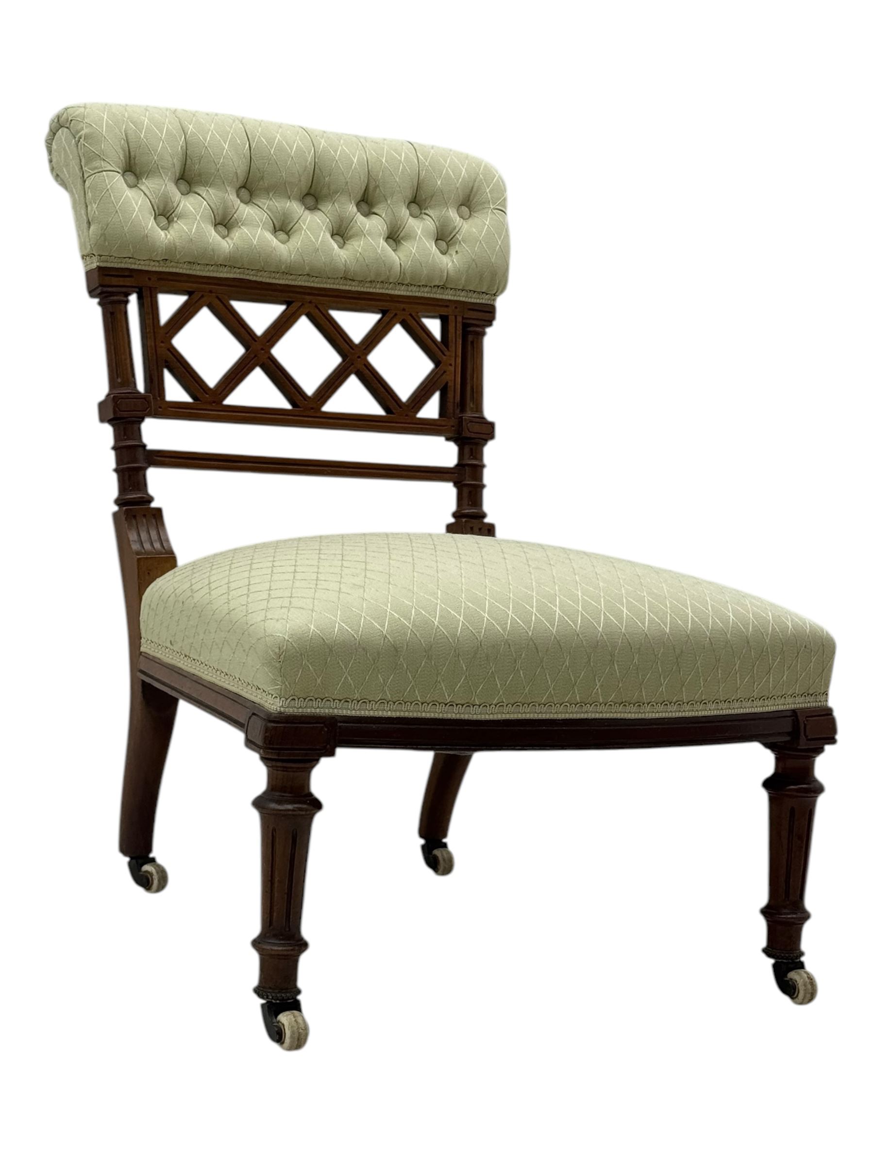 Late Victorian upholstered armchair, with high camel back and deep seat, padded arms and backrest in crimson and cream damask-style fabric, raised on turned ebonised front supports with ceramic castors (H88cm, W65cm, D 60m); and an Edwardian bedroom chair with button upholstered rail back (H72cm, D64cm, W53cm) (2)