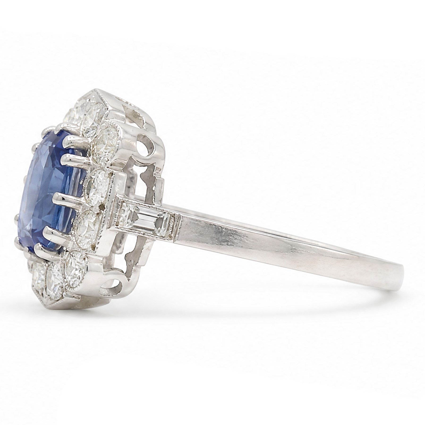 Platinum sapphire an diamond cluster ring, single modified cushion cut sapphire of approx 1.40 carat, surrounded by milgrain set round brilliant cut diamonds and baguette diamond shoulders, hallmarked, total diamond weight approx 0.80 carat