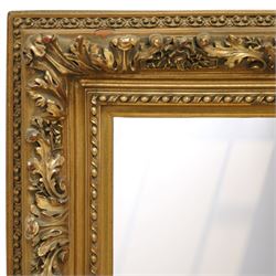 Rococo revival style giltwood and gesso wall mirror, the rectangular frame with layered mouldings, the main frieze carved with scrolling acanthus leaves and stylised floral detail, the inner edge enriched with bead-and-reel moulding, enclosing a rectangular mirror plate