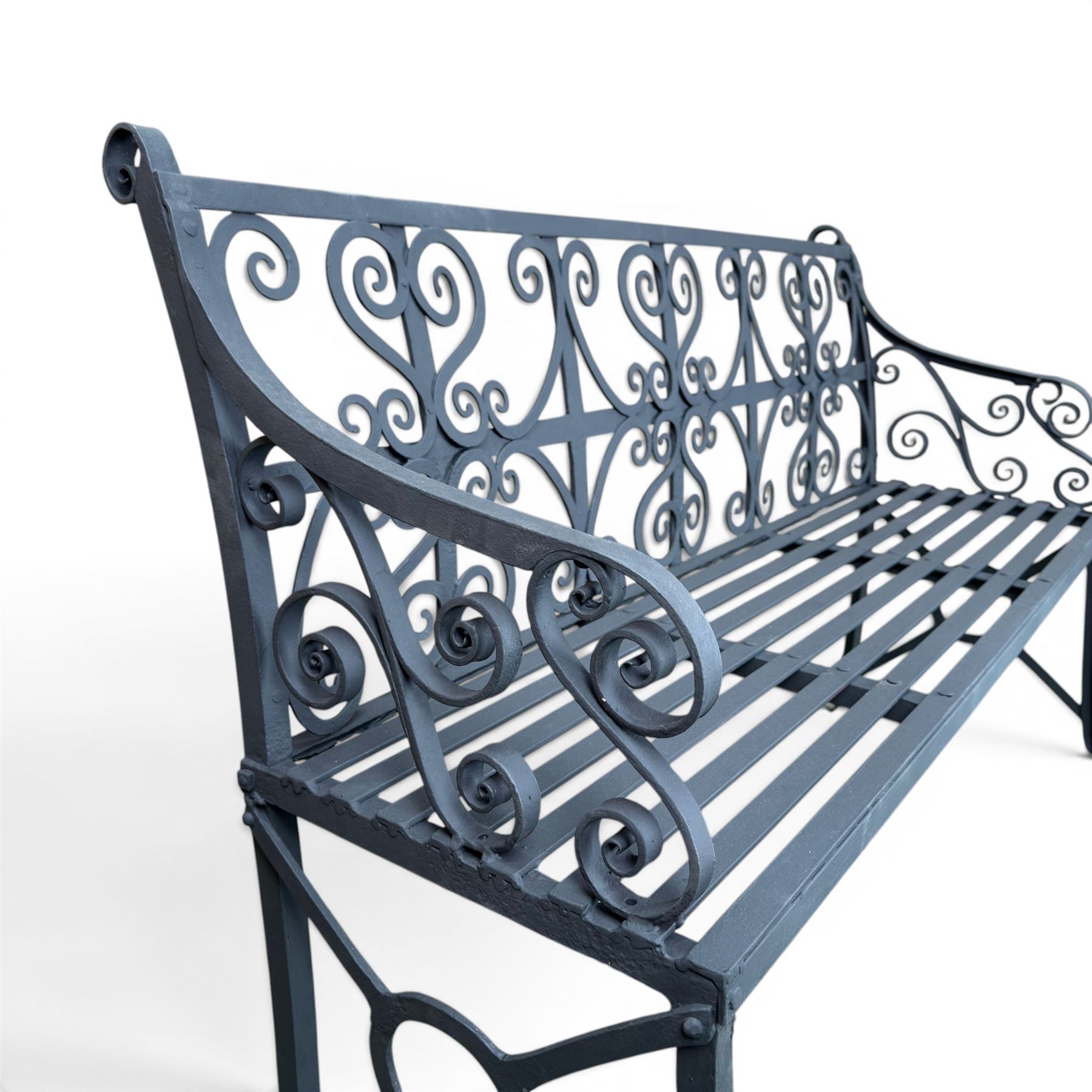Regency period wrought iron garden bench, hand forged in wrought iron and finished in matt black paint, decorated with intricate scrollwork and featuring circular geometric ends, strapwork seat