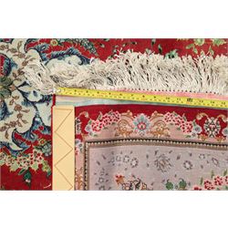 Persian silk inlaid crimson ground Kashan rug, the central shaped field with a floral pole medallion surrounded by trailing floral motifs and festoons of flowerheads, the wide cyan guard line with repeating palmettes and scrolling floral vines