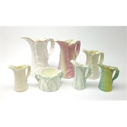 A group of six Royal Worcester leaf moulded porcelain jugs, largest with pink toned glaze, H17.5cm, plus a similarly modelled twin handled sucrier. (7).