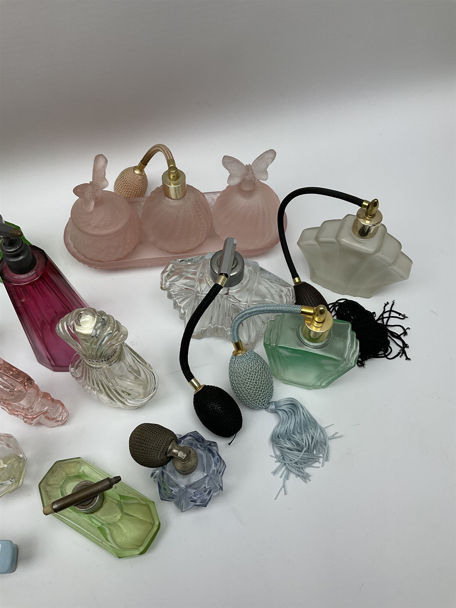 Art Deco style glass perfume bottles and atomisers, to include a large amber example with stopper of fan shape, H18cm, green glass examples with metal stoppers, and a number of other Art Deco style coloured bottles of geometric form with stoppers and mounts