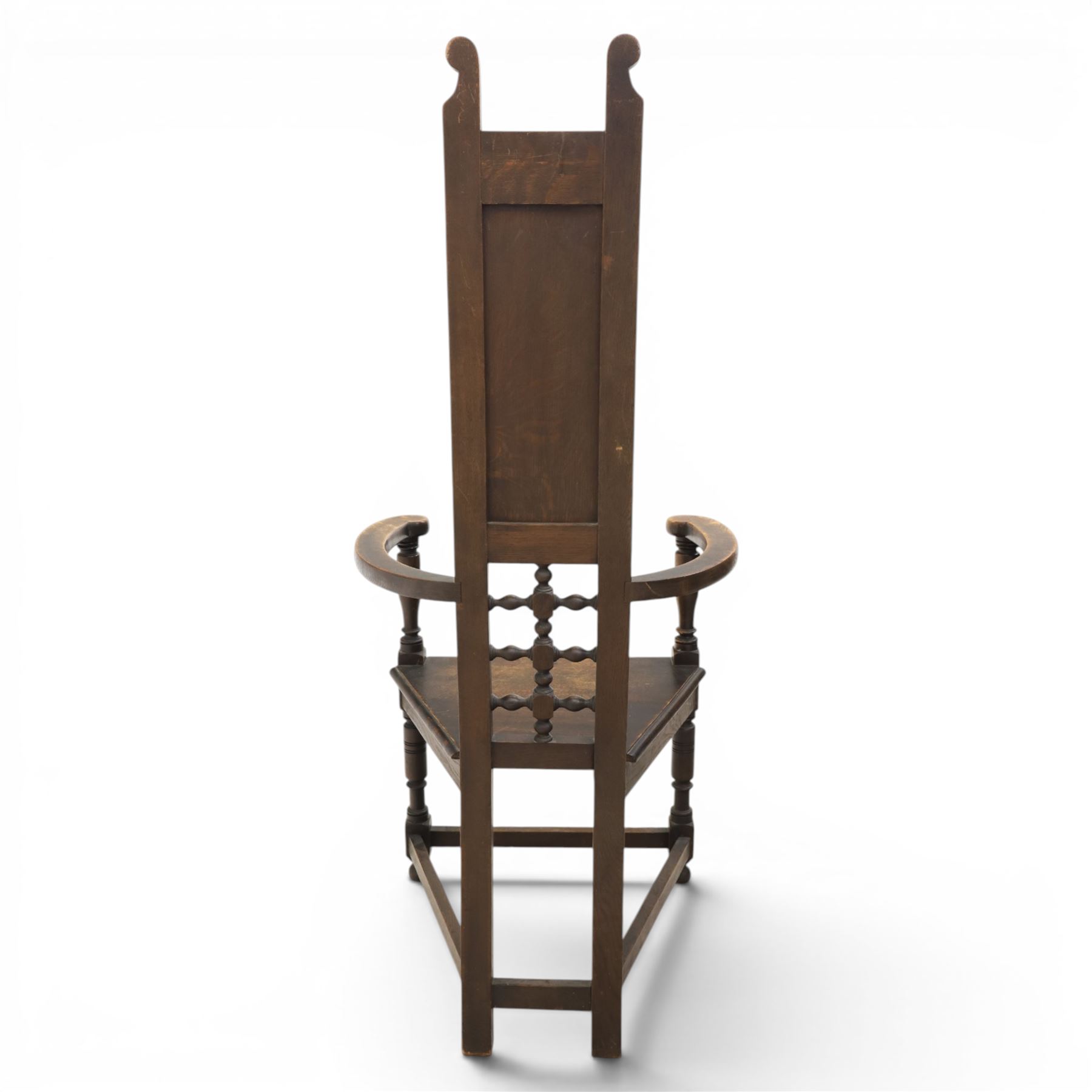 Manner of Liberty & Co. - Arts & Crafts oak Shakespeare chair, high back over triangular seat, flanked by swept arms, raised on turned and block supports united by stretchers
