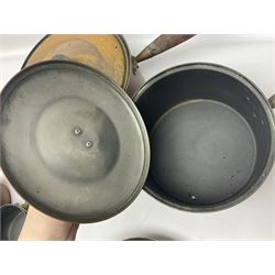 Four Victorian copper moulds, together with a graduating set of copper pans with wooden handles and finials to covers, largest pan 