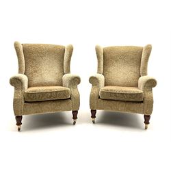 Pair of Parker Knoll armchairs, upholstered in a beige floral patterned fabric, turned supports and castors