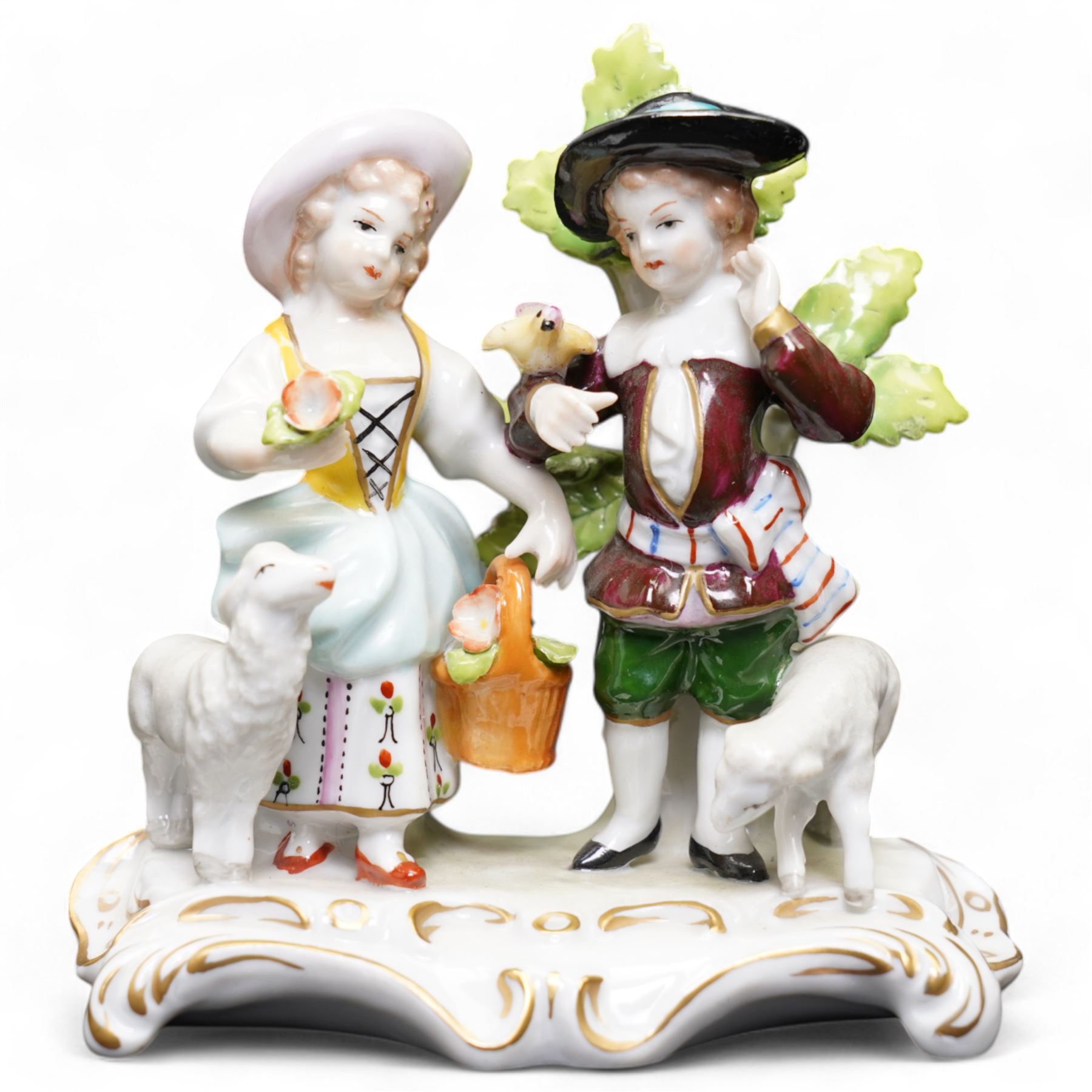 Group of Sitzendorf porcelain figures, one modelled as two children with birds and lambs, the others holding and offering flowers, each upon gilt detailed base, with painted marks beneath (4)