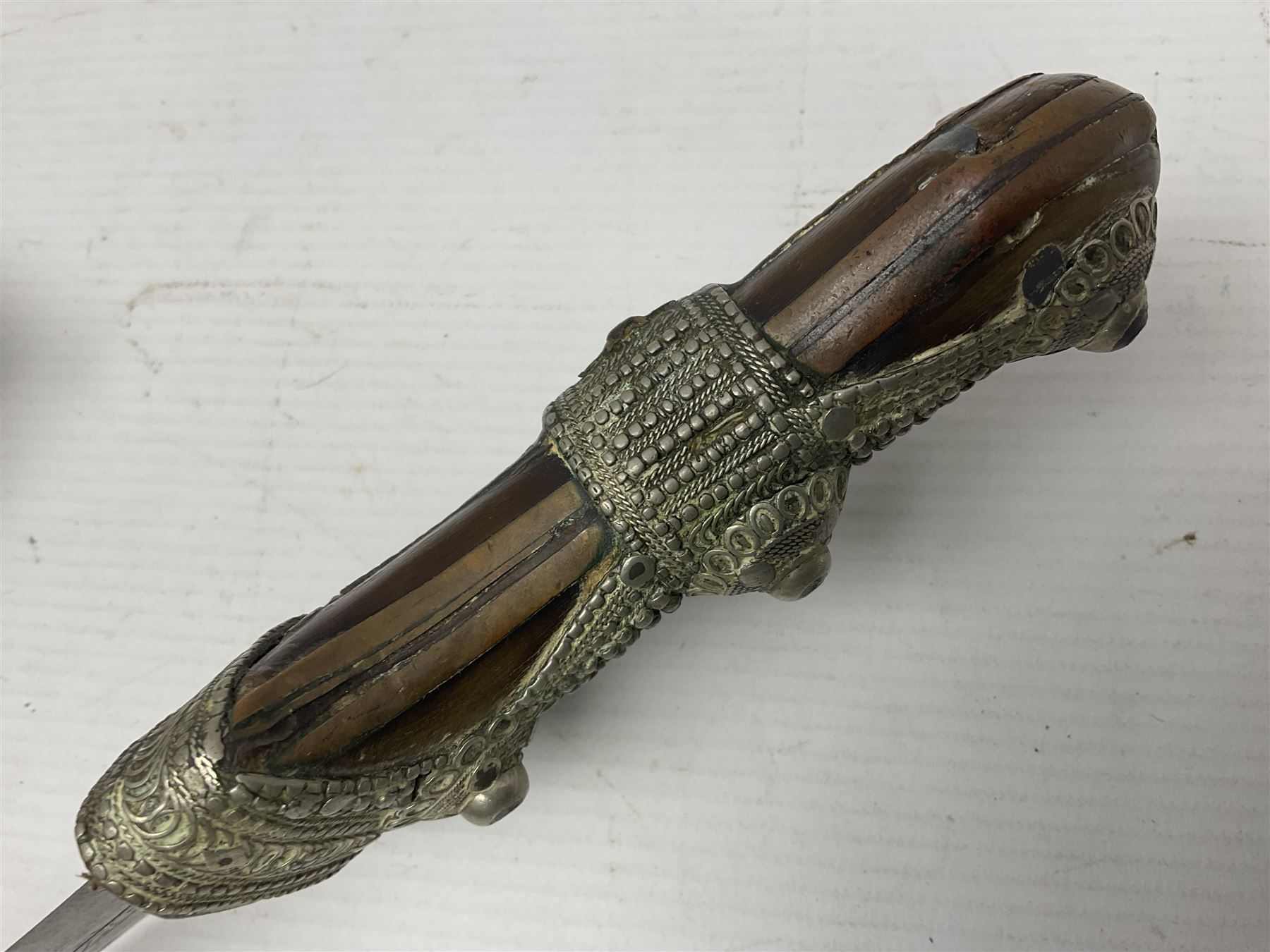 Saudi Arabian khanjar dagger with 29.5cm curving double edged  steel blade; white metal and copper mounted horn grip; in white metal mounted brass and leather scabbard incorporating embroidered leather wearing strap