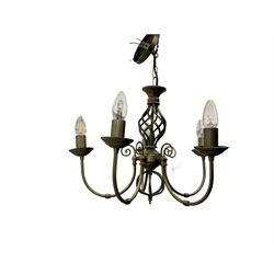 Pair of brass five-branch chandeliers, each featuring scrolling arms with candle-style light fittings, centred by a twisted openwork column, complete with ceiling roses and hanging chains