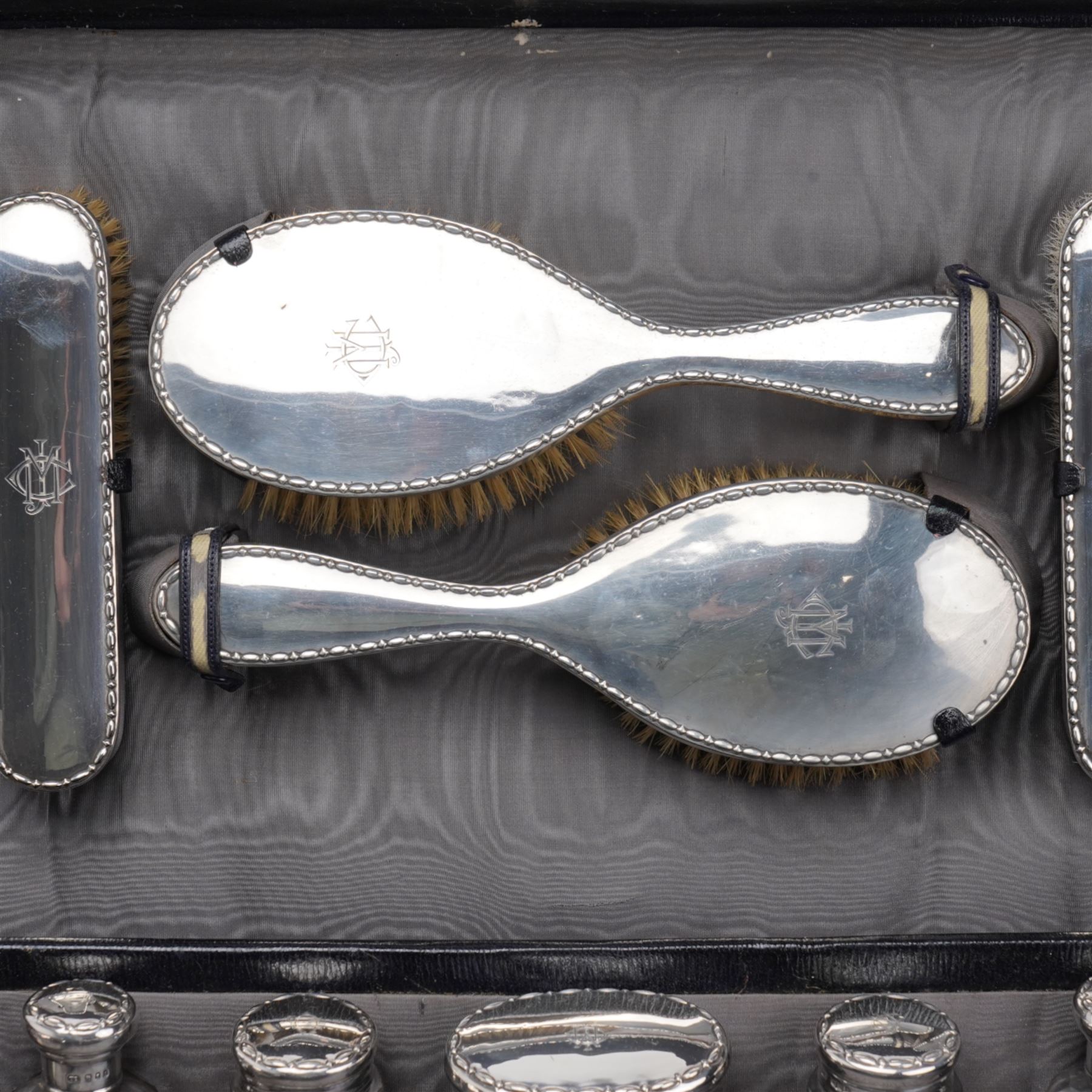 Early 20th century ladies leather travelling dressing case marked Walker & Hall, with watered silk interior and contents of silver mounted glass jars, dressing table set, leather blotter etc and with outer canvas London 1921/22 Maker Thomas Ingleton 46cm x 31cm 