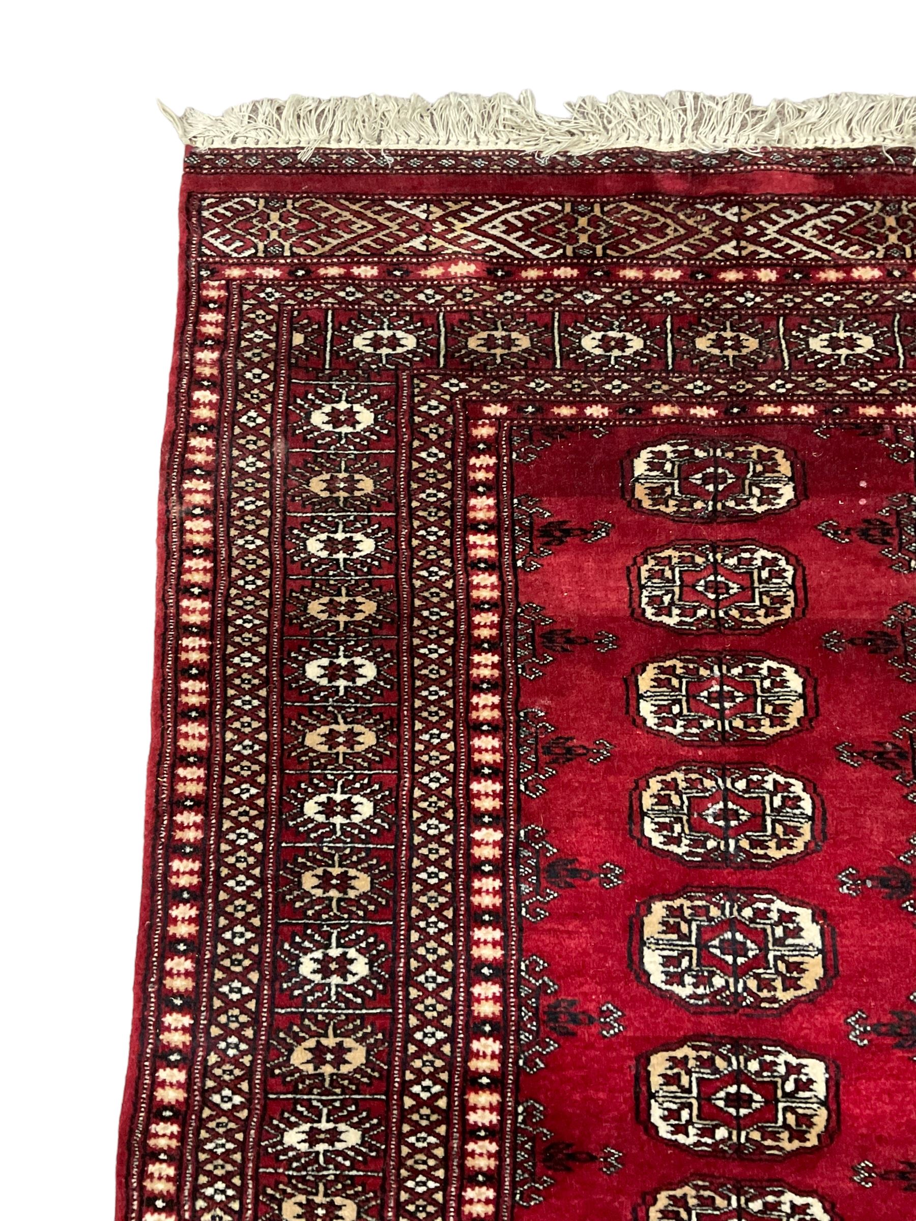 Persian Bokhara rug, red ground and decorated with single row of Gul motifs, multiple band border with geometric design