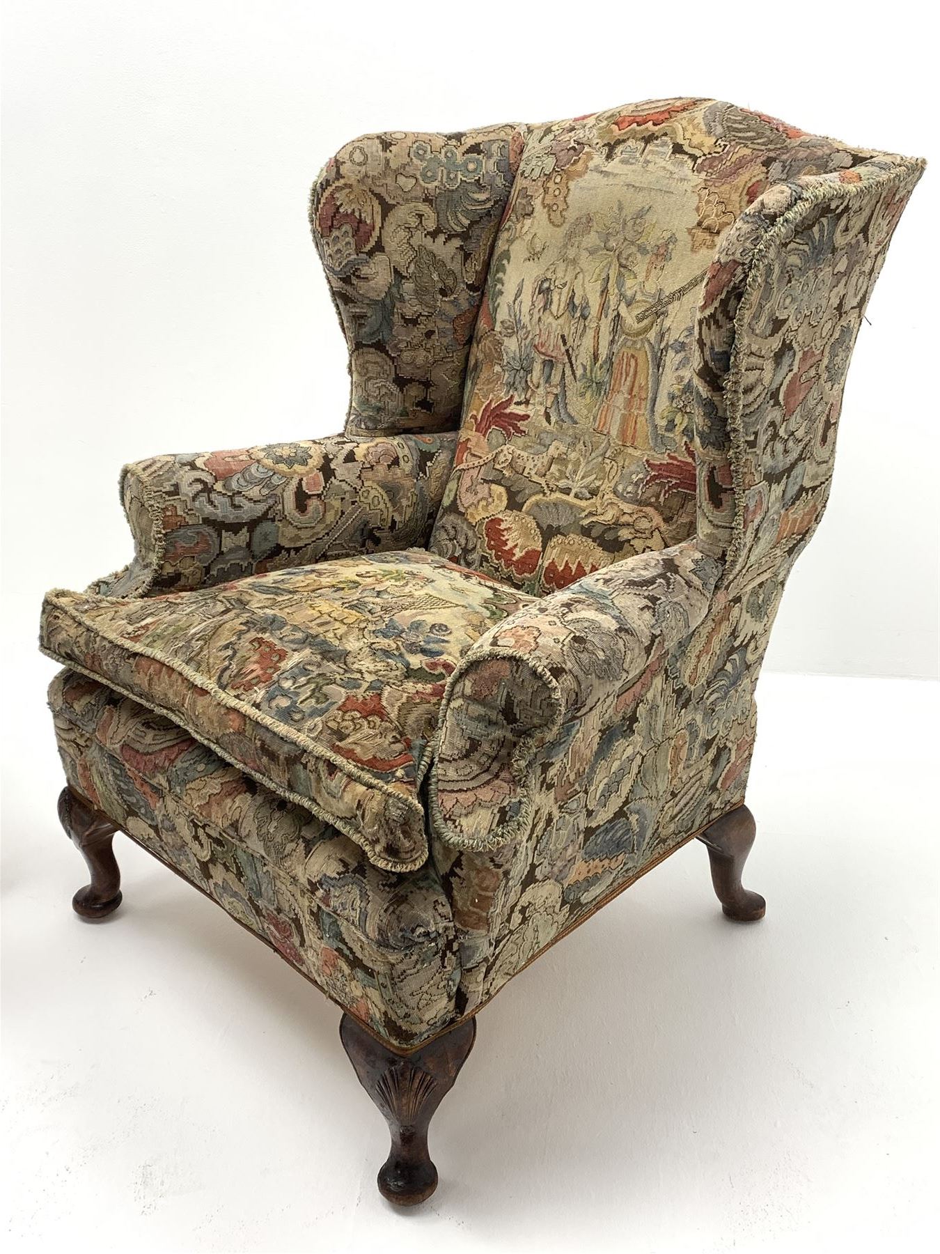 Matched pair early 20th century Queen Anne style wingback armchairs, walnut framed, sprung seats with seat cushions upholstered in needle work cover, shell carved cabriole front feet