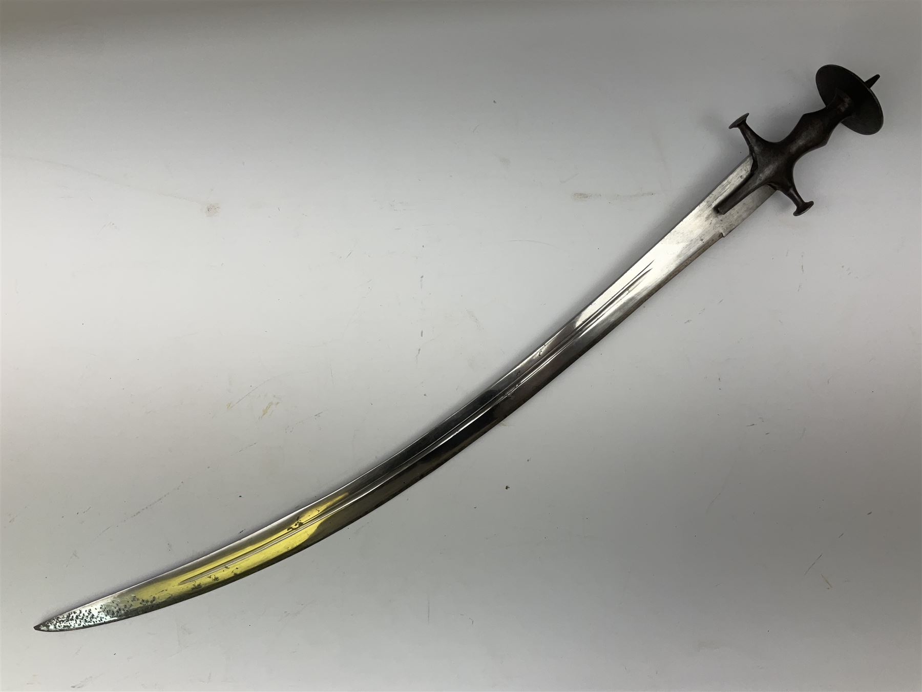 19th Century Indian Tulwar sword with 77cm single edged, slightly curved fullered blade;  steel crossguard, langets, grip and spiked disc pommel with stiff leaf decoration L90cm overall