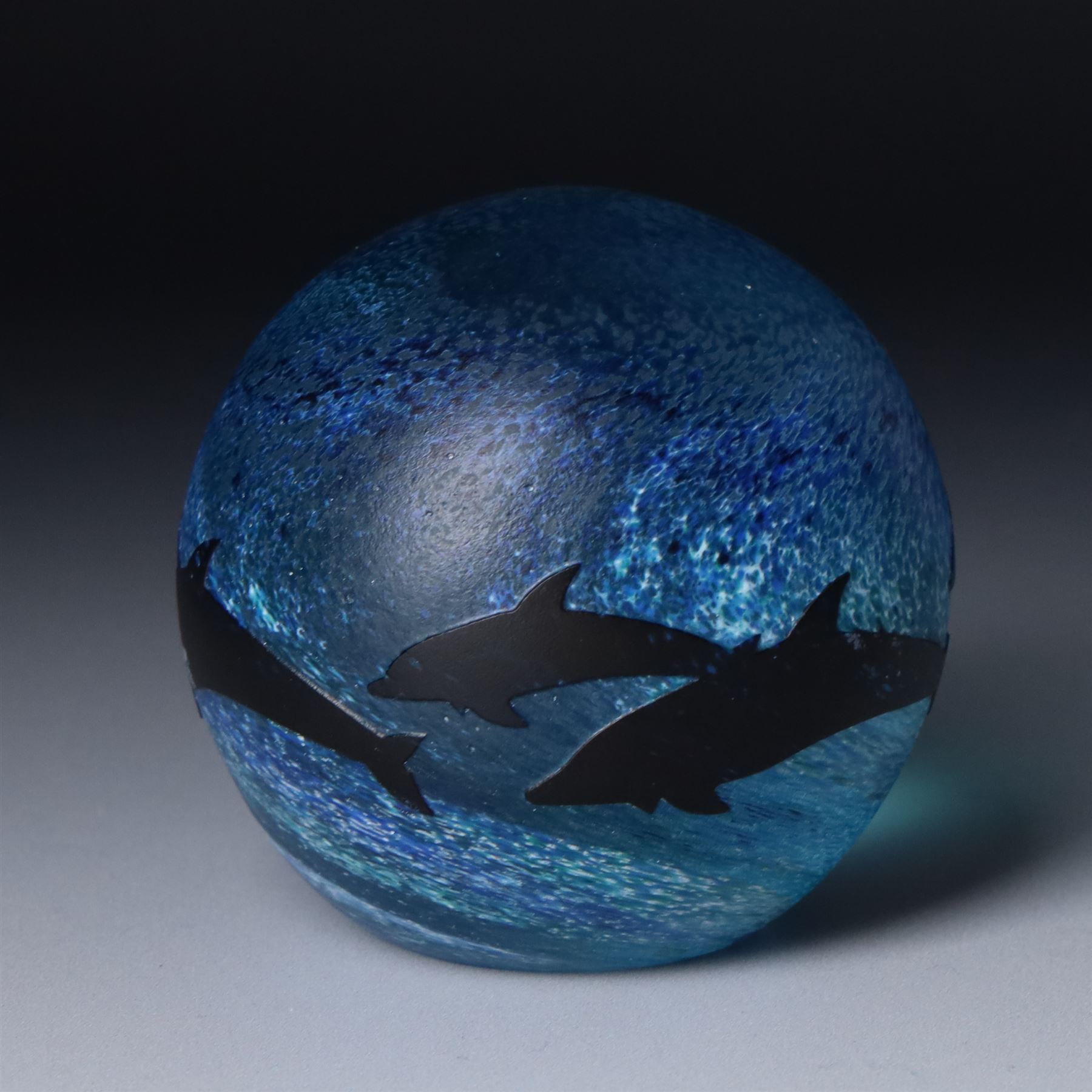 Malcolm Sutcliffe (British 1954-): Studio glass cameo bowl, the body mottled and speckled with shades of blue decorated with dolphins, etched signature, D18cm and matching paperweight (2)