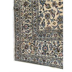 Persian Kashan ivory ground carpet, the field decorated with interlacing leafy branches and stylised plant motifs, repeating border with multiple guards