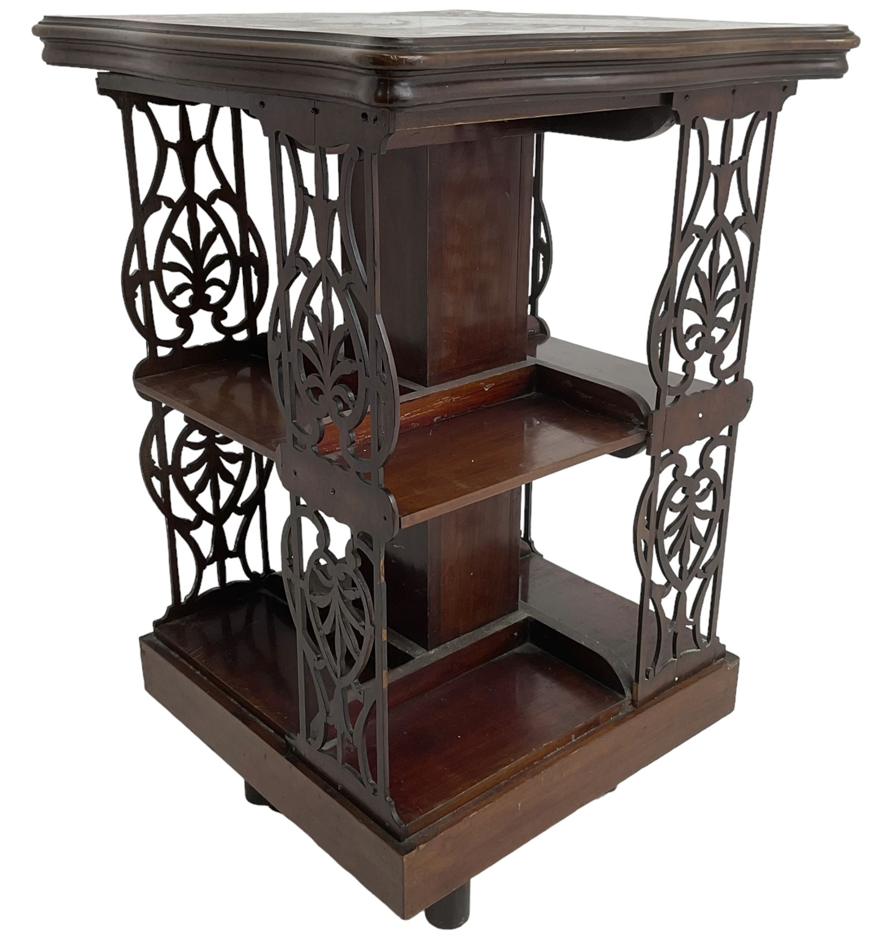 Edwardian mahogany revolving bookcase, the shaped moulded top inlaid with cusped panel and trailing bellflowers within a satinwood frame, foliate pierced upright splats and central square column supporting two tiers, on cruciform base with brass and ceramic castors 