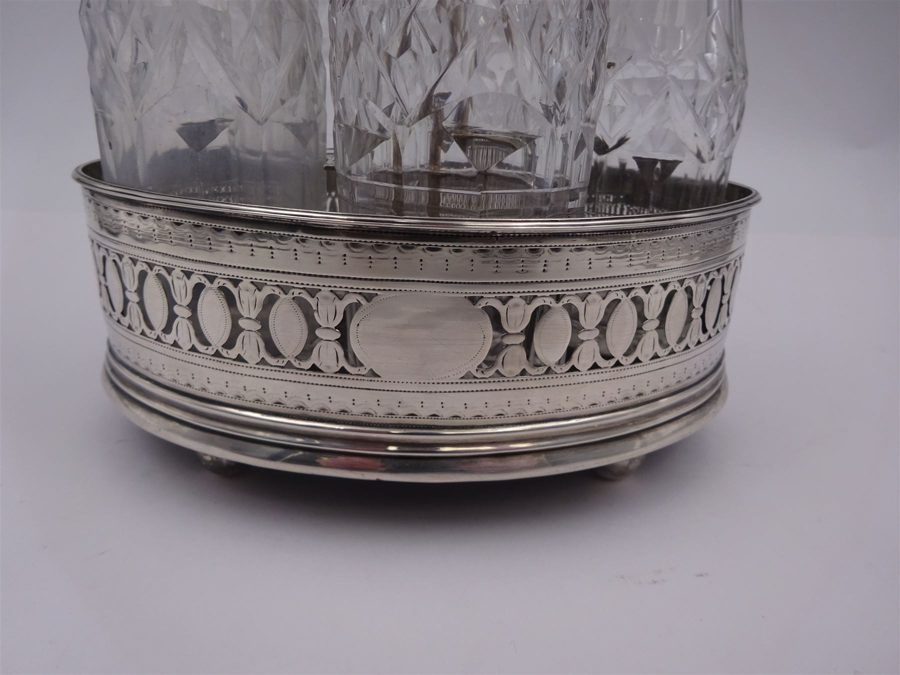 Late 18th century silver cruet stand, of oval form, with pierced sides upon four bun feet, hallmarked to handle Hester Bateman, all other hallmarks indistinct, together with five matched silver mounted cut glass cruet bottles, including some later Victorian examples, hallmarks predominantly indistinct, stand H20cm