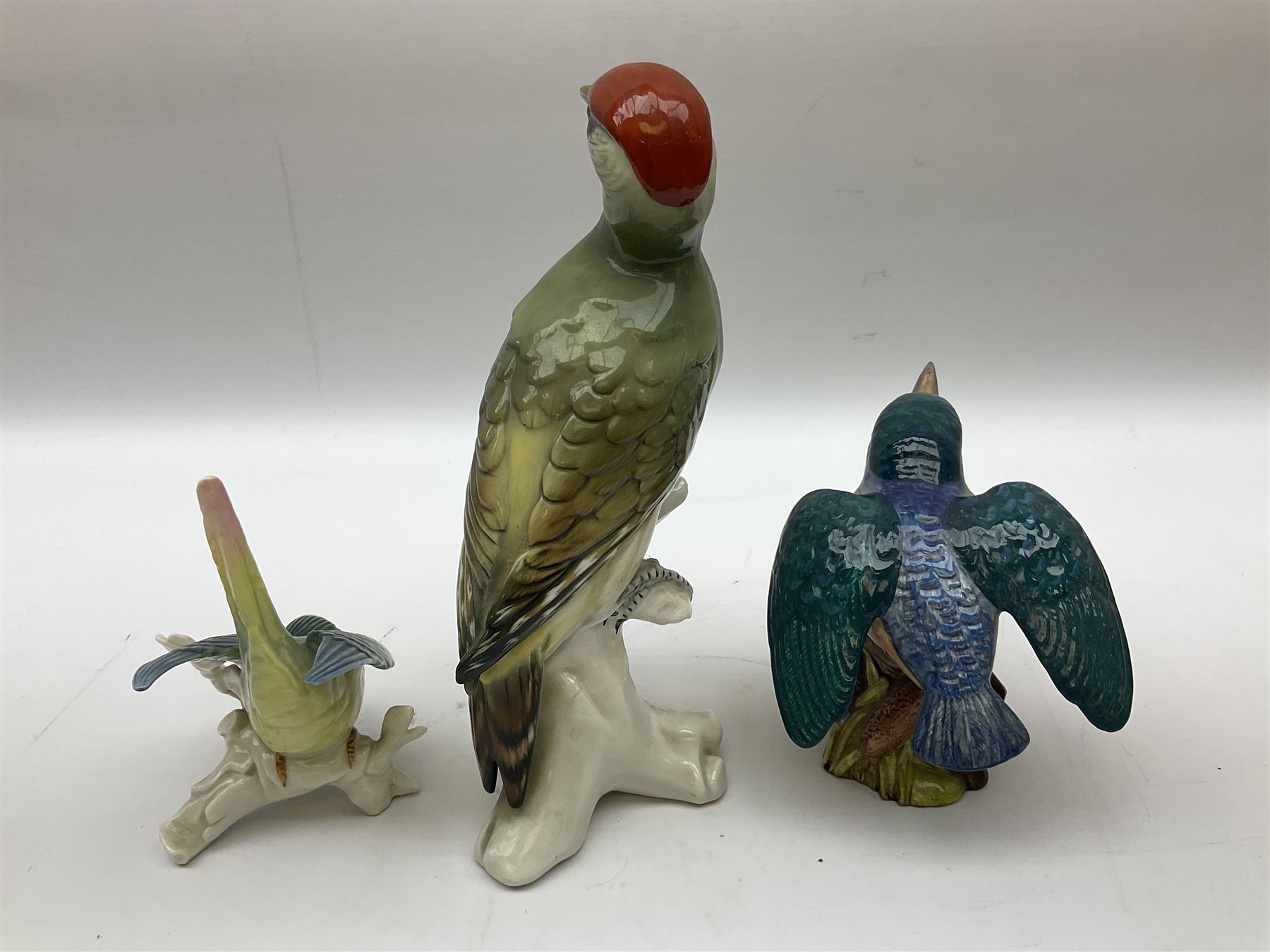 Karl Ens figure of a green woodpecker, modelled perched upon branch, model no. 7527, together with Karl Ens figure of budgie and Beswick Kingfisher no. 2371, all with printed marks beneath, tallest H25cm