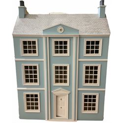 Georgian style wooden double fronted three-storey dolls house with pale blue stucco finish under a faux tiled roof with two chimney stacks, the double hinged front opening to reveal six fully decorated rooms with floor coverings, central staircase, porcelain fitted bathroom, kitchen with deep white sink and Aga cooker, electric lighting with adaptor, fully furnished with French style and other furniture, grand piano etc, and comprehensive range of accessories H82cm W61cm D31cm