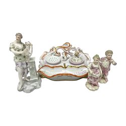 Three Continental figures, comprising a pair modelled as a boy and girl, she with flowers, he with eggs, and a female figure with harp, each probably Volkstedt, together with a Continental porcelain desk stand, (4)