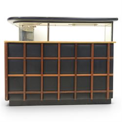 Barget of London - Mid 20th century L-shaped teak and black vinyl cocktail bar, shaped top with gilt metal banding and black cushioned edge over glazed upper section and open serving shelf, the reverse fitted with shelves, the front with applied lattice mouldings over black vinyl, on plinth base