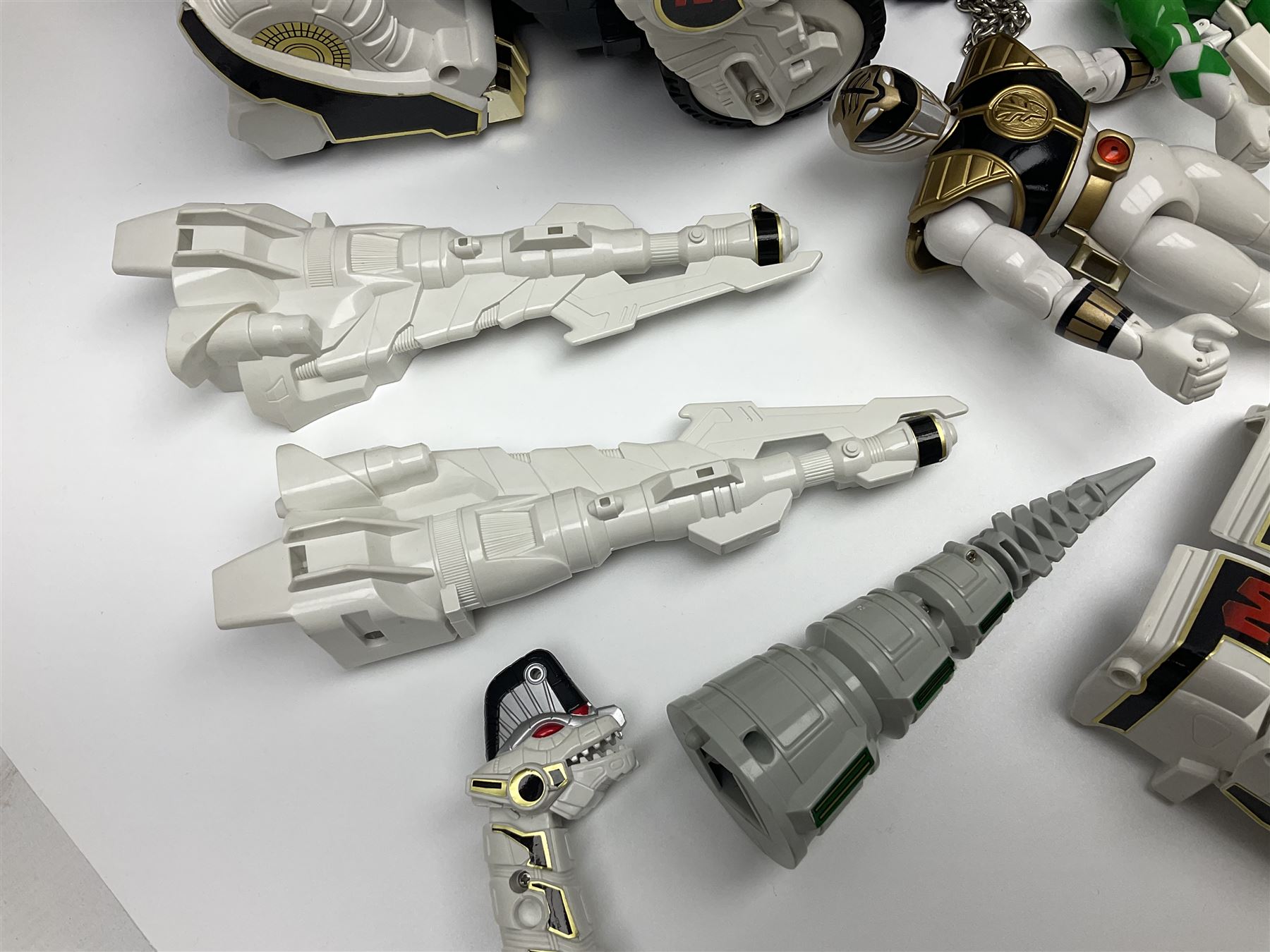 Collection of early 90s Mighty Morphin’ Power Rangers Zords, figures and accessories. Titanus the Carrier Zord, marked Bandai 1991; Green Dragonzord, incomplete; 1994 White Tigerzord with original instruction manual; 1993 Triceratops Dinozord, Mastodon Dinozord and Sabertooth Tiger Dinozord, Pterodactyl Dinozord, missing guns; with 1993 Power Morpher and original Power Coins, with further related figures, accessories and weapons