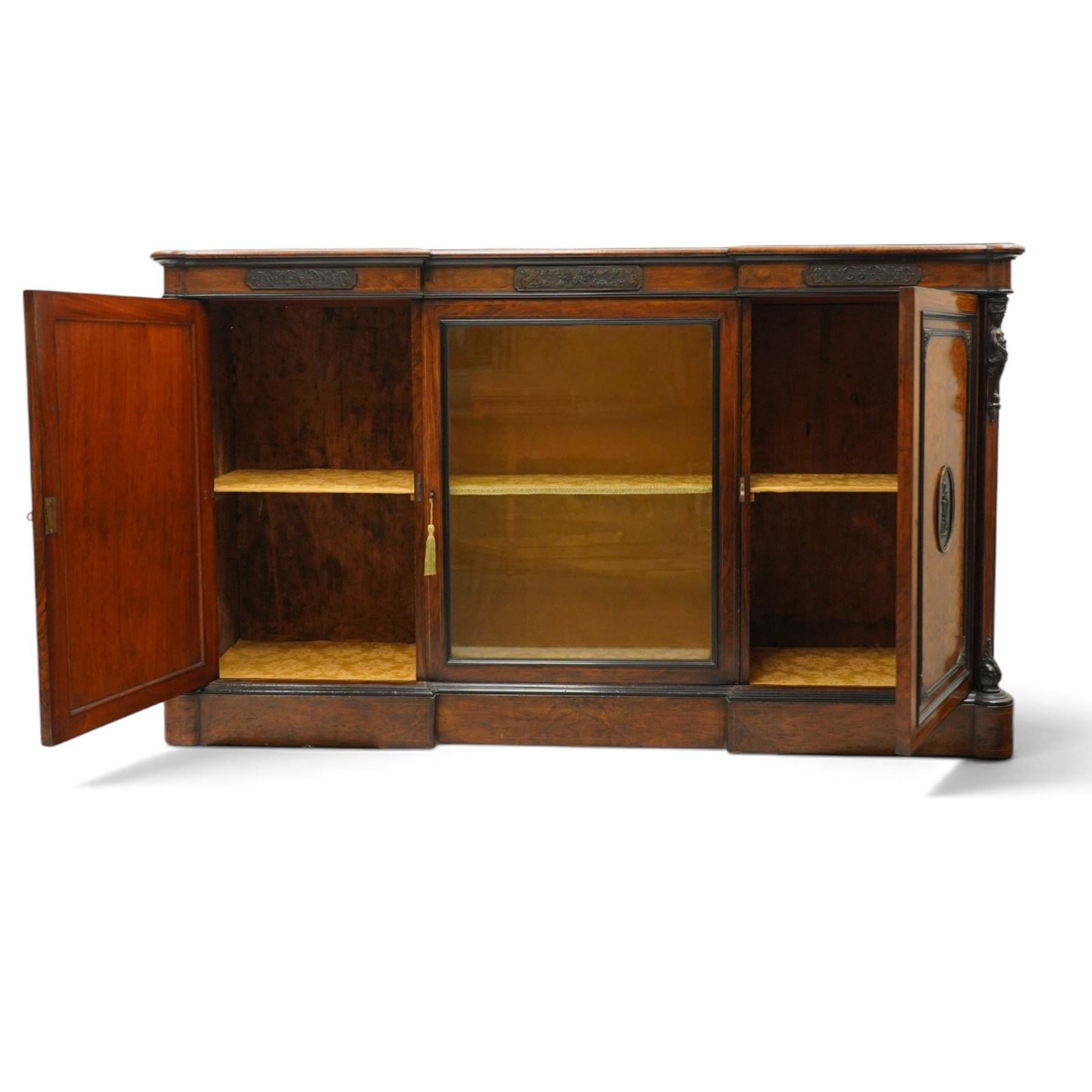 Lamb of Manchester (est. 1843) - Victorian Aesthetic Movement inlaid figured and burr walnut inverted-breakfront credenza, the shaped rectangular top with ebony banding and boxwood stringing, the frieze applied with bronze mounts decorated with foliate and scroll motifs, fitted with central glazed door flanked by panelled doors with central oval metal plaques depicting Classical Muses with lyre, the flanking canted uprights applied with caryatid maidens holding torches, acanthus terminal over skirted base