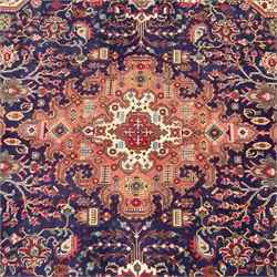 North West Persian carpet, the indigo field centred by a large terracotta and ivory medallion with matching pendants, decorated throughout with stylised palmettes, flowerheads and branching foliage, ivory geometric floral spandrels, enclosed by a red palmette border and narrow patterned guard bands