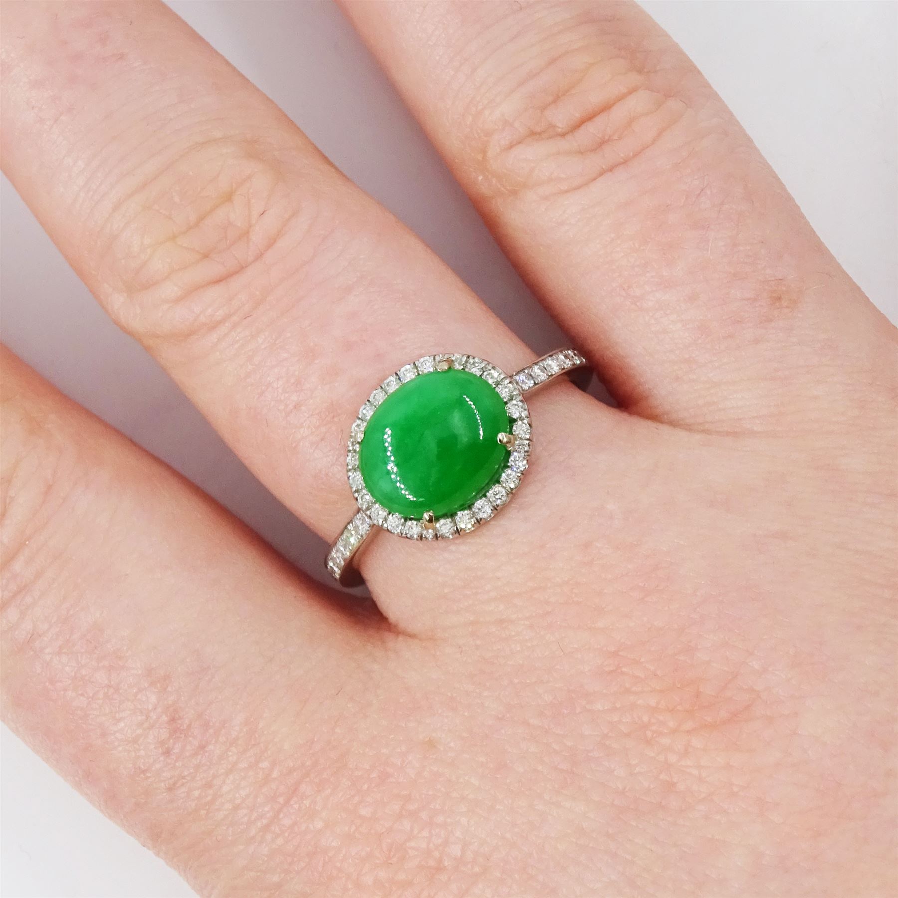 Platinum jadeite and diamond cluster ring, single oval cabochon cut jadeite of 2.20 carat, surrounded by round brilliant cut diamonds and diamond set shoulders, stamped Plat