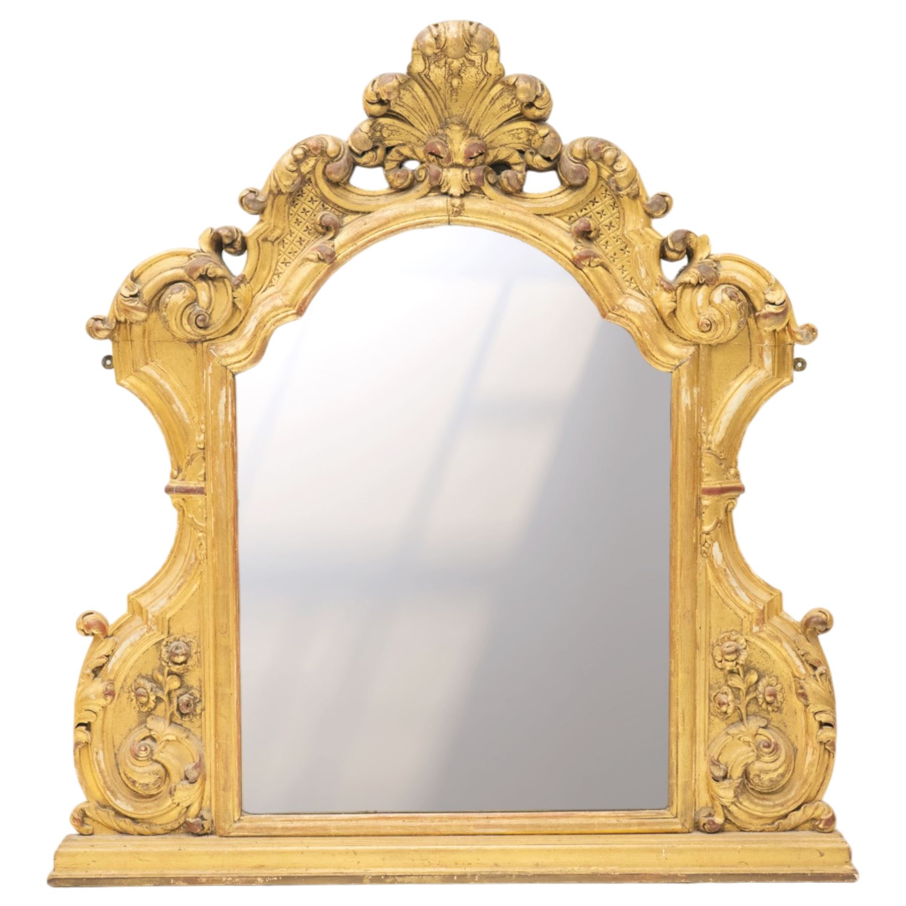 19th century Italian Baroque Revival carved giltwood and gesso wall mirror, the large acanthus leaf pediment flanked by C-scrolls and further acanthi motifs, enclosing a shaped arch plate with moulded slip, flanked by down-scrolls of acanthi with emerging flowering branches, on a stepped base