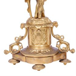Pair of 19th century ormolu putto figures, each modelled stood with foliate support to backs, upon a naturalistic base upon cylindrical plinth each with twin leafy tendril supports, each plinth with inset Sevres type painted panel of a cherub, upon a shaped base with four compressed disk feet, the front facing with leaf mount, H29cm