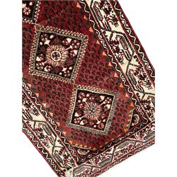 Persian Baluch red ground runner, seven lozenge medallions each decorated with stylised floral motifs, ivory border decorated with trailing pattern and Boteh motifs, within geometric guard stripes 