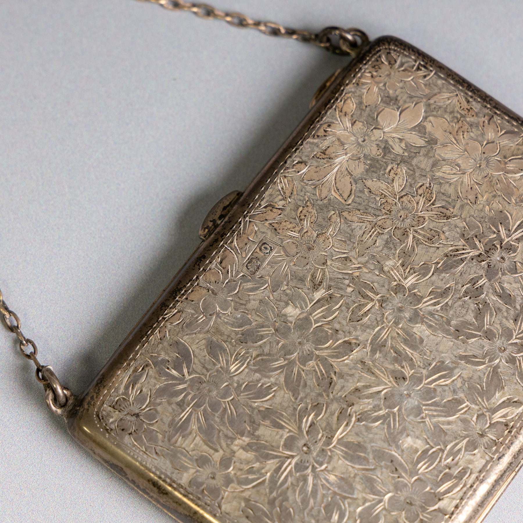 Early 20th century silver coin purse, with floral decoration and finger chain, hallmarked together with an early 20th century cigarette case,  with engraved initials, hallmarked and a silver filigree cigarette case