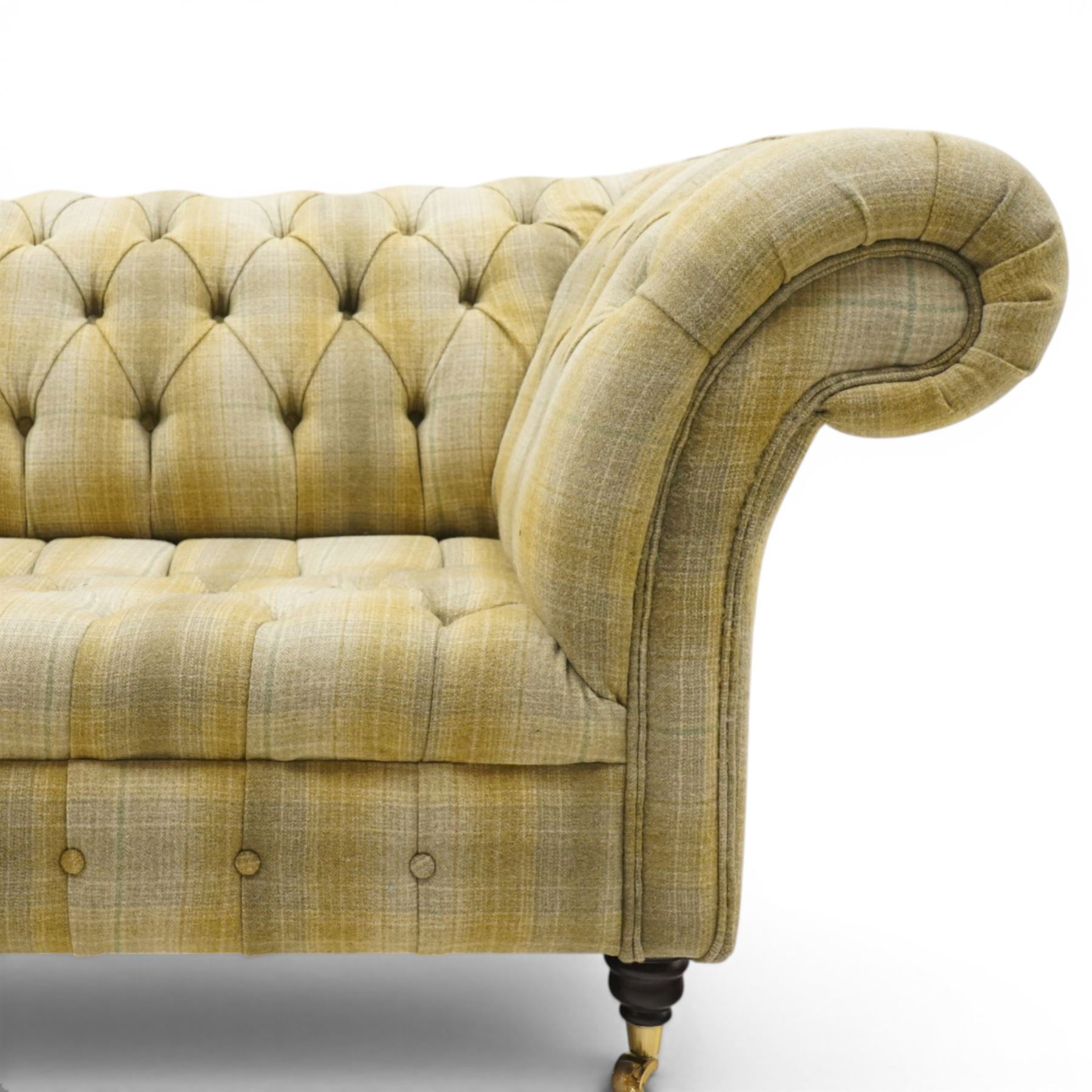Late 20th century Chesterfield style two seat sofa, upholstered in muted green and yellow tartan fabric with buttoned back, arms and seat, on turned front supports with brass castors