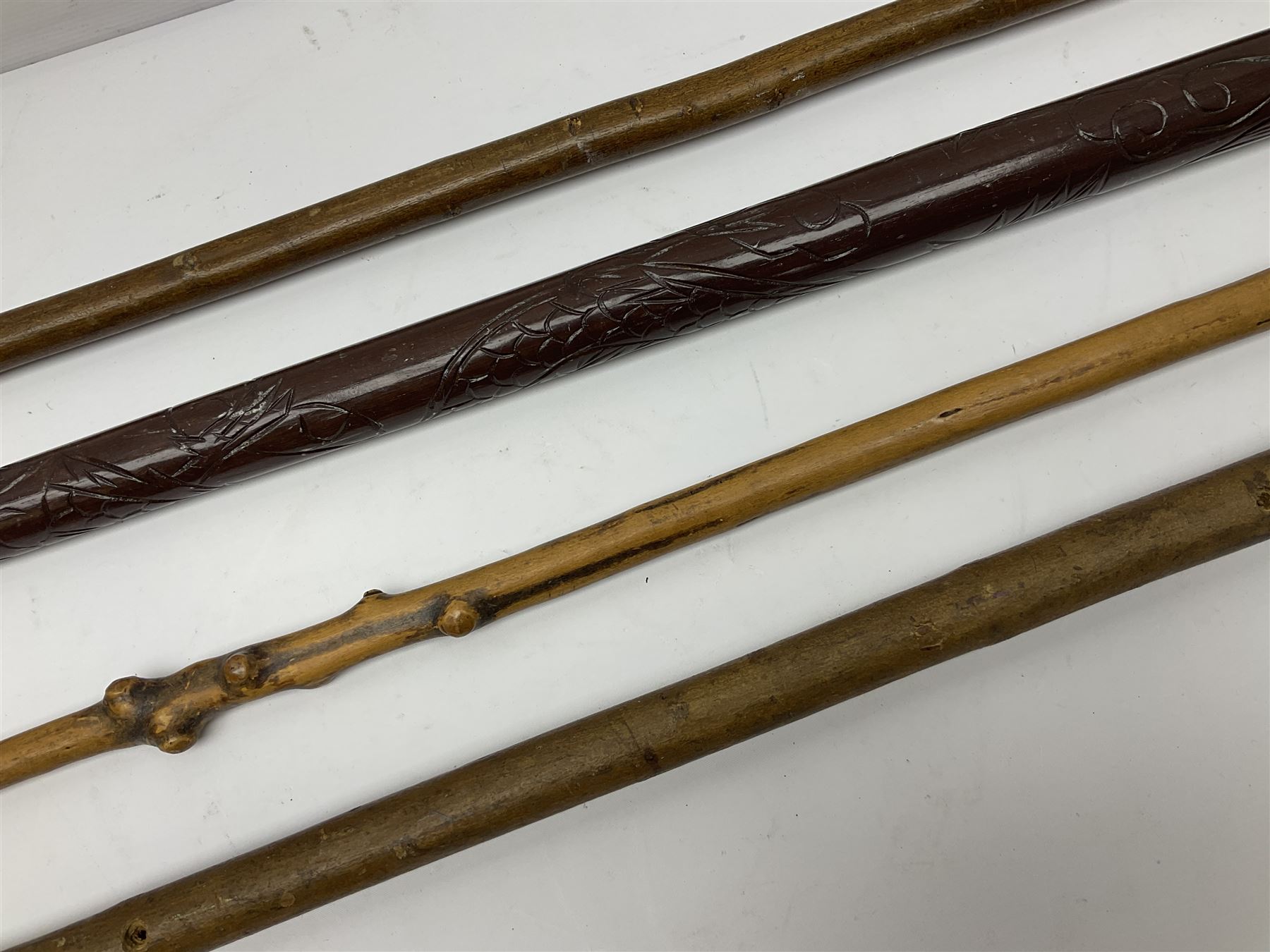 Four wooden walking canes, including a carved mahogany snooker cue example, tallest H86cm