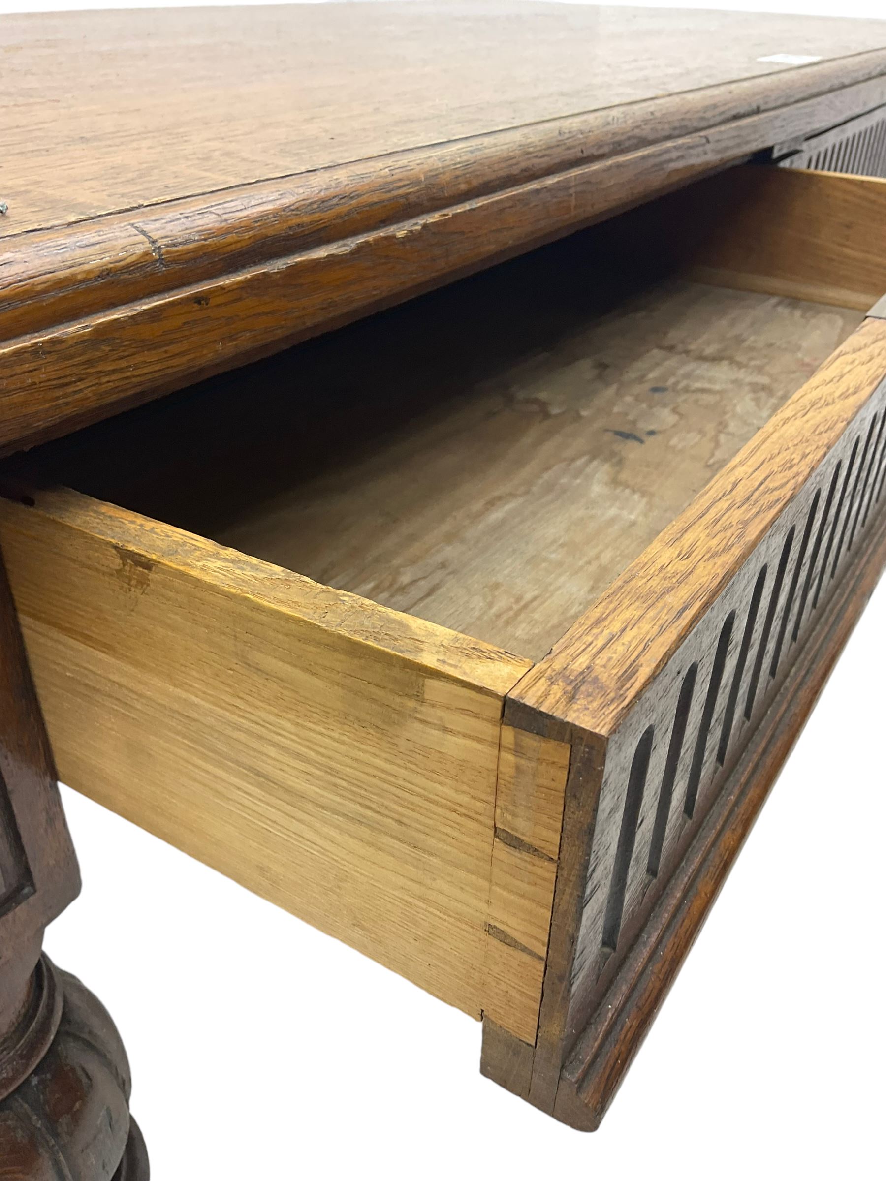 Late 19th century oak library table, moulded rectangular top with canted corners, fitted with two frieze drawers with fluted facias, on lobe carved and fluted turned supports 
