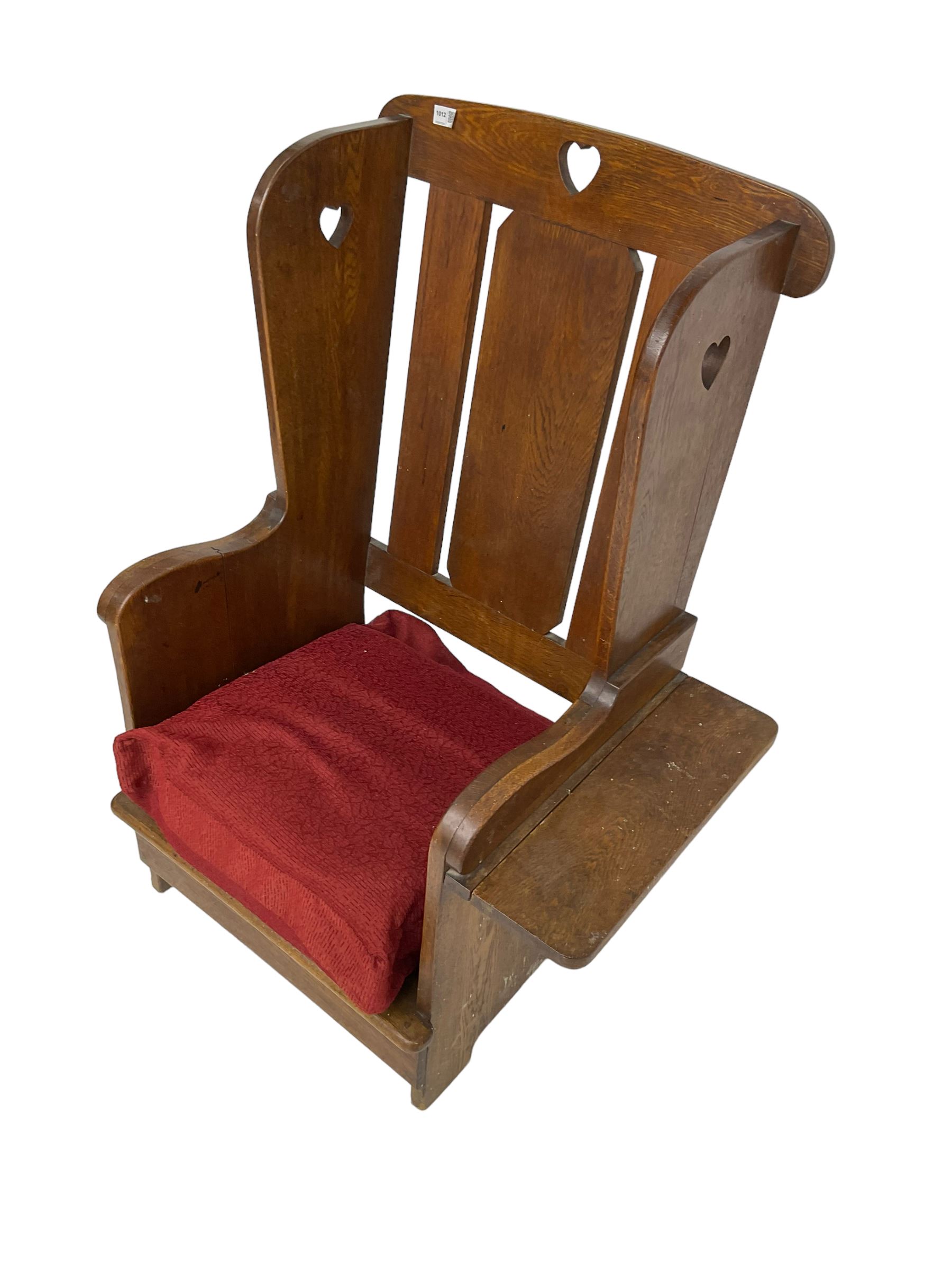 Arts and Crafts design oak reading wingback armchair, high back with pierced heart design, drop-leaf side table to one arm