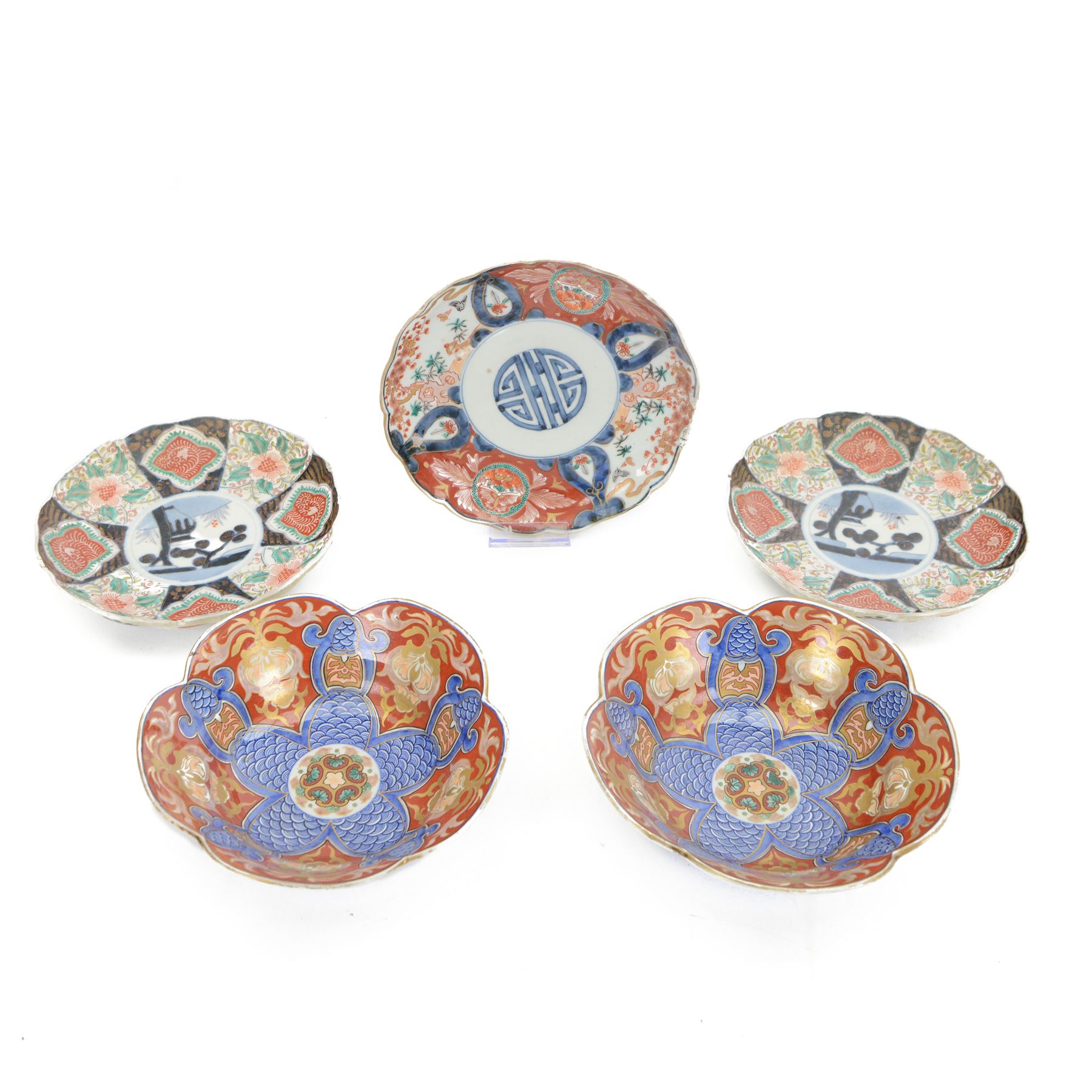 Group of 19th century Japanese Imari porcelain, Meiji period, comprising pair of lobed dishes, decorated stylised reserves and painels in blue and gilt upon a red ground, H6.5cm D21.5cm, a pair of plates of circular lobed form, decorated with a central panel depicting a vase beneath pine branches, and surrounded by panels of flowers and stylised quatrefoil shapes, D21cm, and another similar example painted with a character in underglaze blue to the centre, with character mark beneath, D22cm, each with character marks beneath               