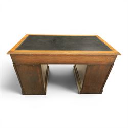 Oak twin pedestal desk with leather top, moulded rectangular top with inset black leather writing surface, nine fielded panelled drawers with brass handles, raised on a plinth base with castors