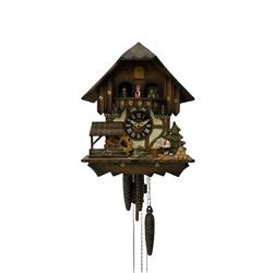 A 20th century West German 30-hour Automaton musical cuckoo clock with a Swiss musical movement playing three tunes, visible pendulum and three cast metal pine cone weights, carved pine wood case with automaton water wheel, woodsman and carousel, chapter ring with Roman numerals and decorative hands, with strike/silence lever.


