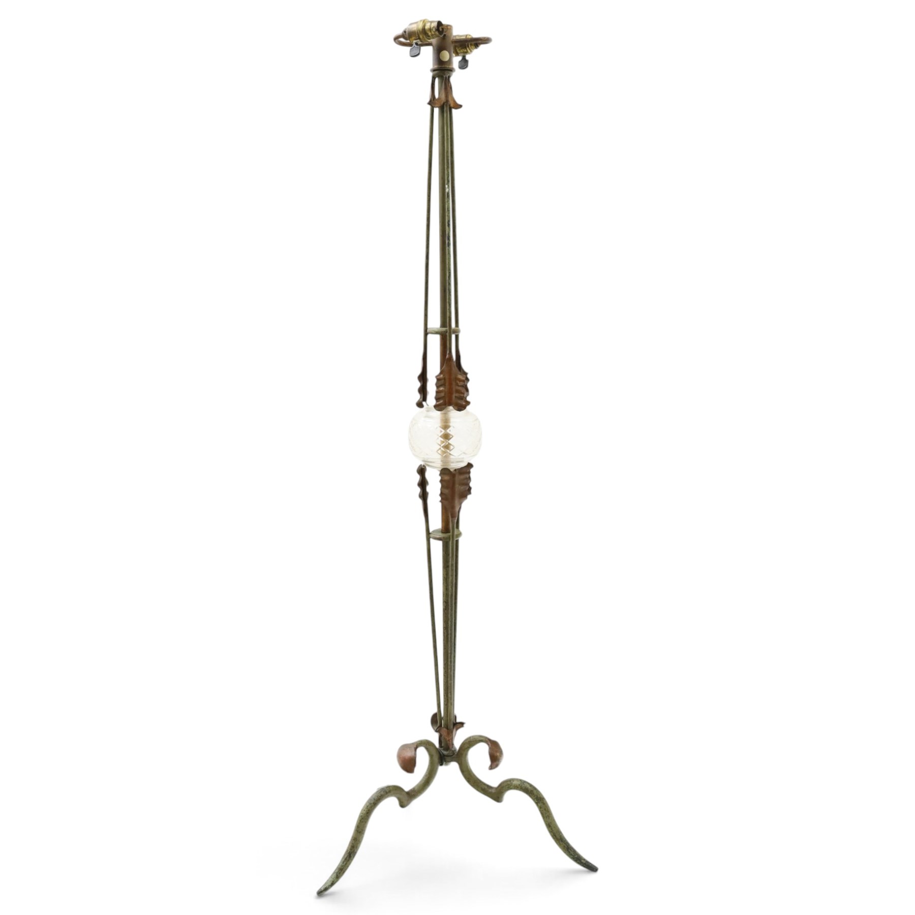 Arts and Crafts wrought iron and copper standard lamp, the openwork stem centred by a cut-glass reservoir with arrow-cut decoration, applied with stylised copper leaves, on shaped tripod base