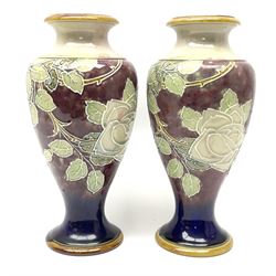 A pair of early 20th century Royal Doulton stoneware vases, of baluster form, decorated with roses and thorny vines against a mottled purple ground, with impressed marks and monogrammed for Florrie Jones beneath, H28cm. 