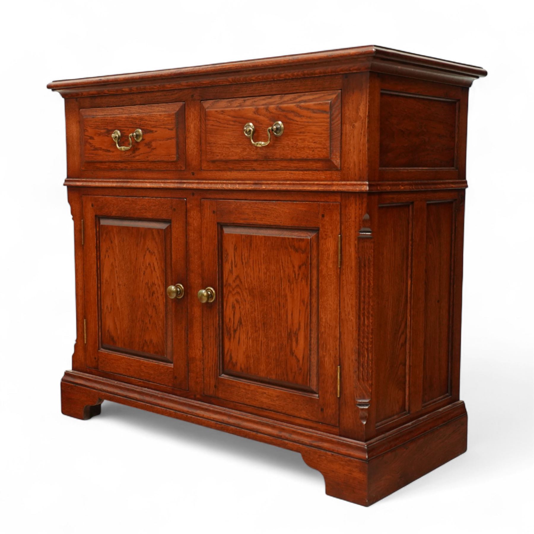 20th century country oak side cabinet, rectangular top over two short drawers and twin panelled cupboard doors, flanked by reeded uprights, on plinth base