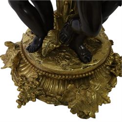 Louis XVI style gilt table lamp, the central column decorated with acanthus leaves, surrounded with three putti with vine leaf crowns, upon a circular base adorned with grape and vines, with shade, H64cm