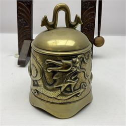 Chinese brass temple bell, decorated in high relief with a a dragon chasing a flaming pearl, within a carved floral hardwood stand, H36cm