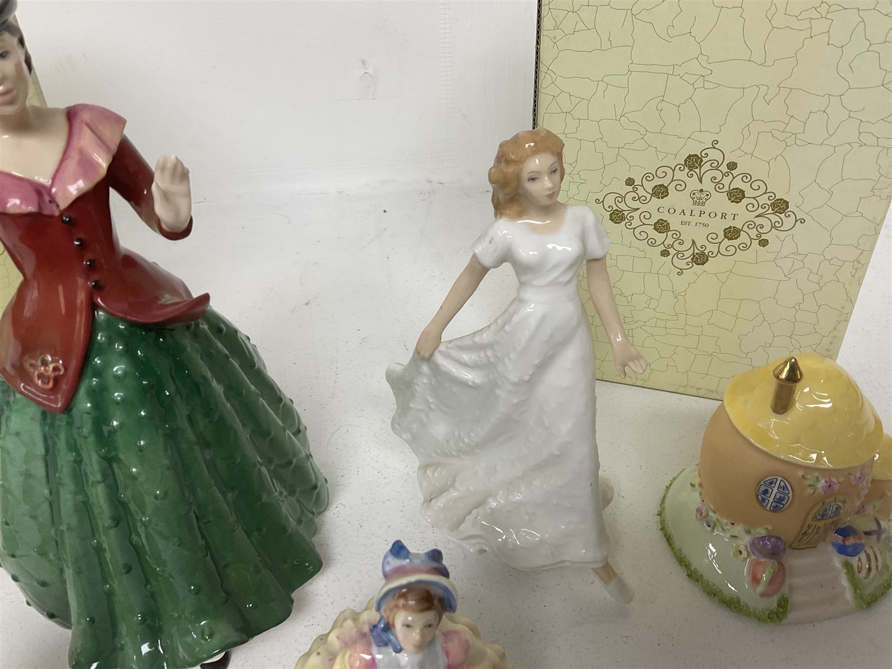 Two Coalport cottages, comprising Teapot cottage and Easter Cottage, together with four Royal Doulton figures, including Holly and Friendship 