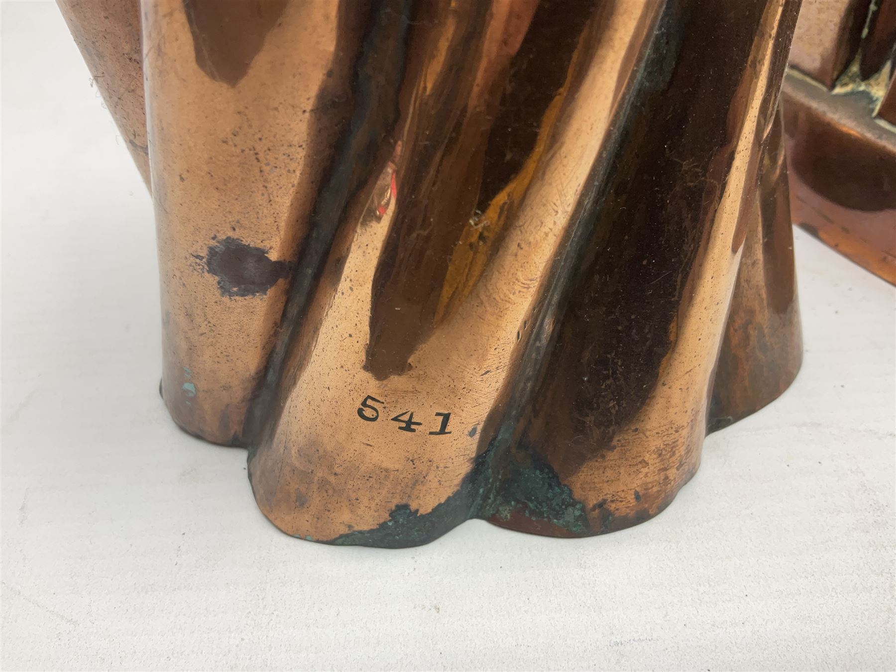 Four Victorian copper moulds, together with a graduating set of copper pans with wooden handles and finials to covers, largest pan 