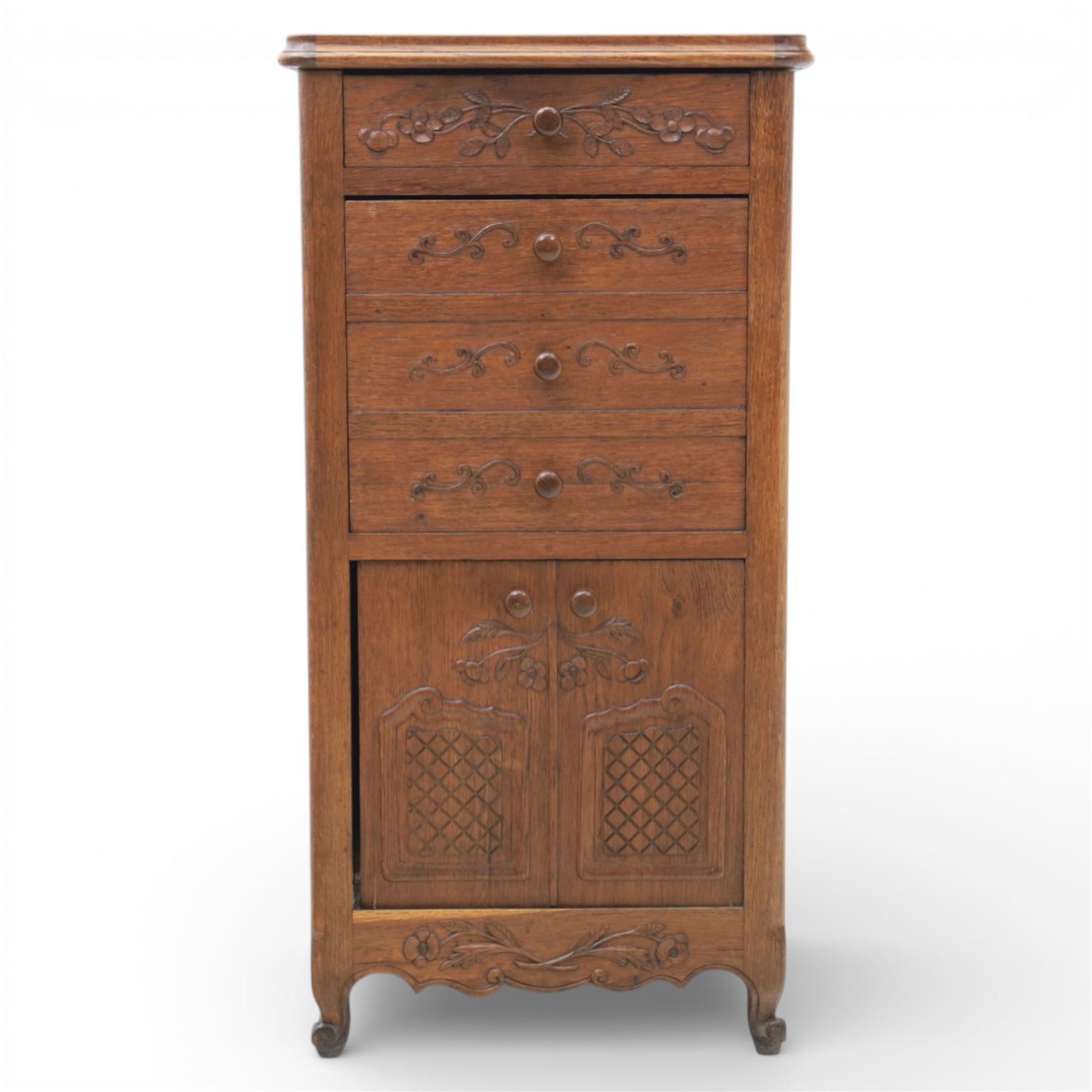 20th century French style oak bedside chest of pedestal form, the top with rounded moulded edge with drop leaf to the back, above five carved drawers with applied scroll ornament and turned knobs, the cupboard base with twin carved doors with diamond lattice panels, with shaped apron and bracket feet